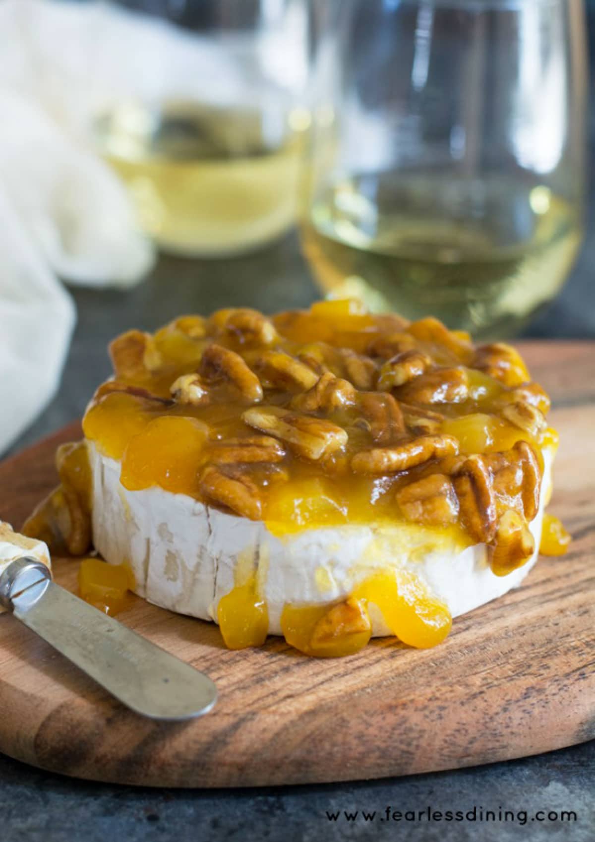 A pecan brie appetizer topped with a mango pecan sauce.