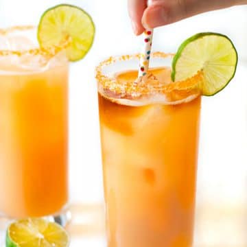 Two glasses of pog cocktail with polka dot straws.