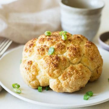 A whole roasted cauliflower on a plate.