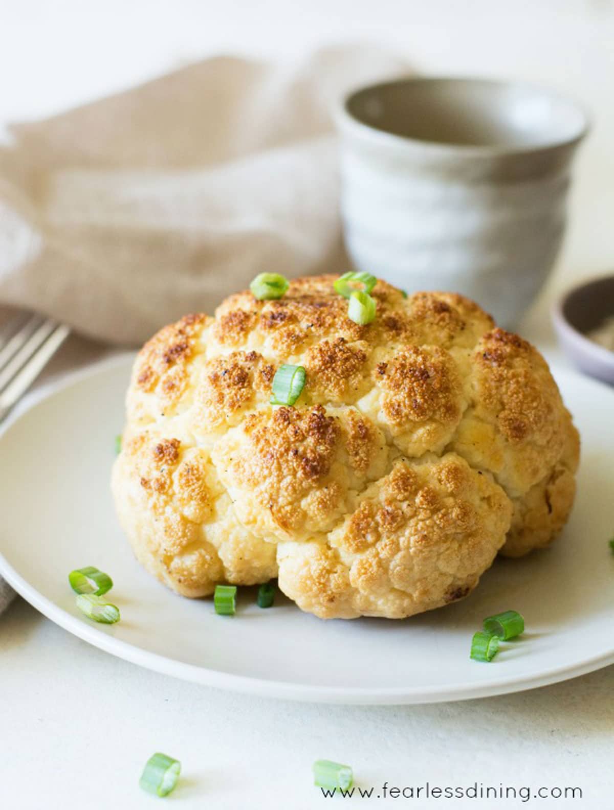 A whole roasted cauliflower on a plate.