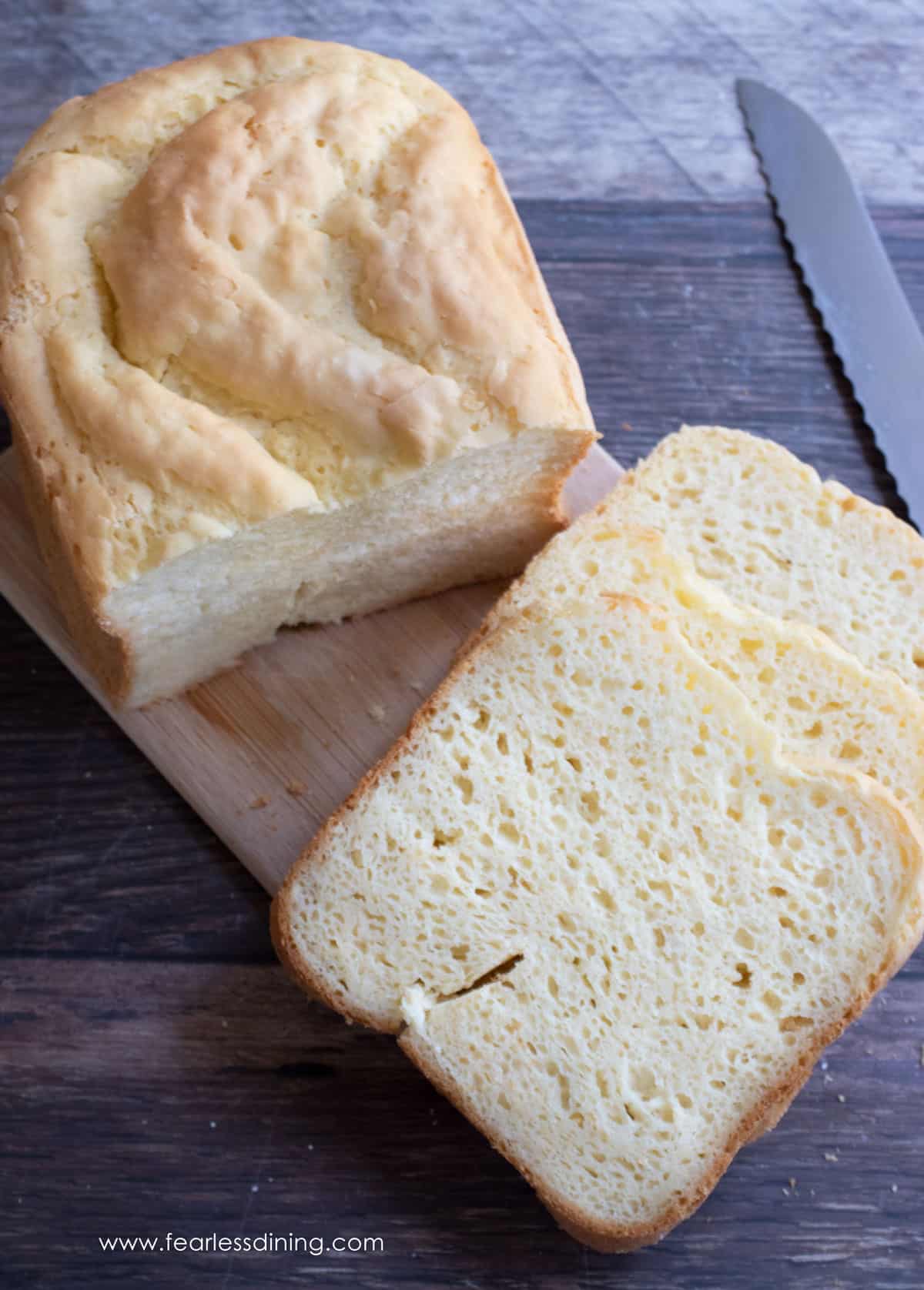 A loaf of gluten-free bread made, with Cup4Cup, and sliced on a cutting board.