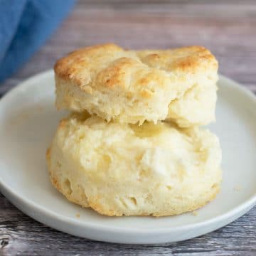 A biscuit cut in half on a plate with butter.