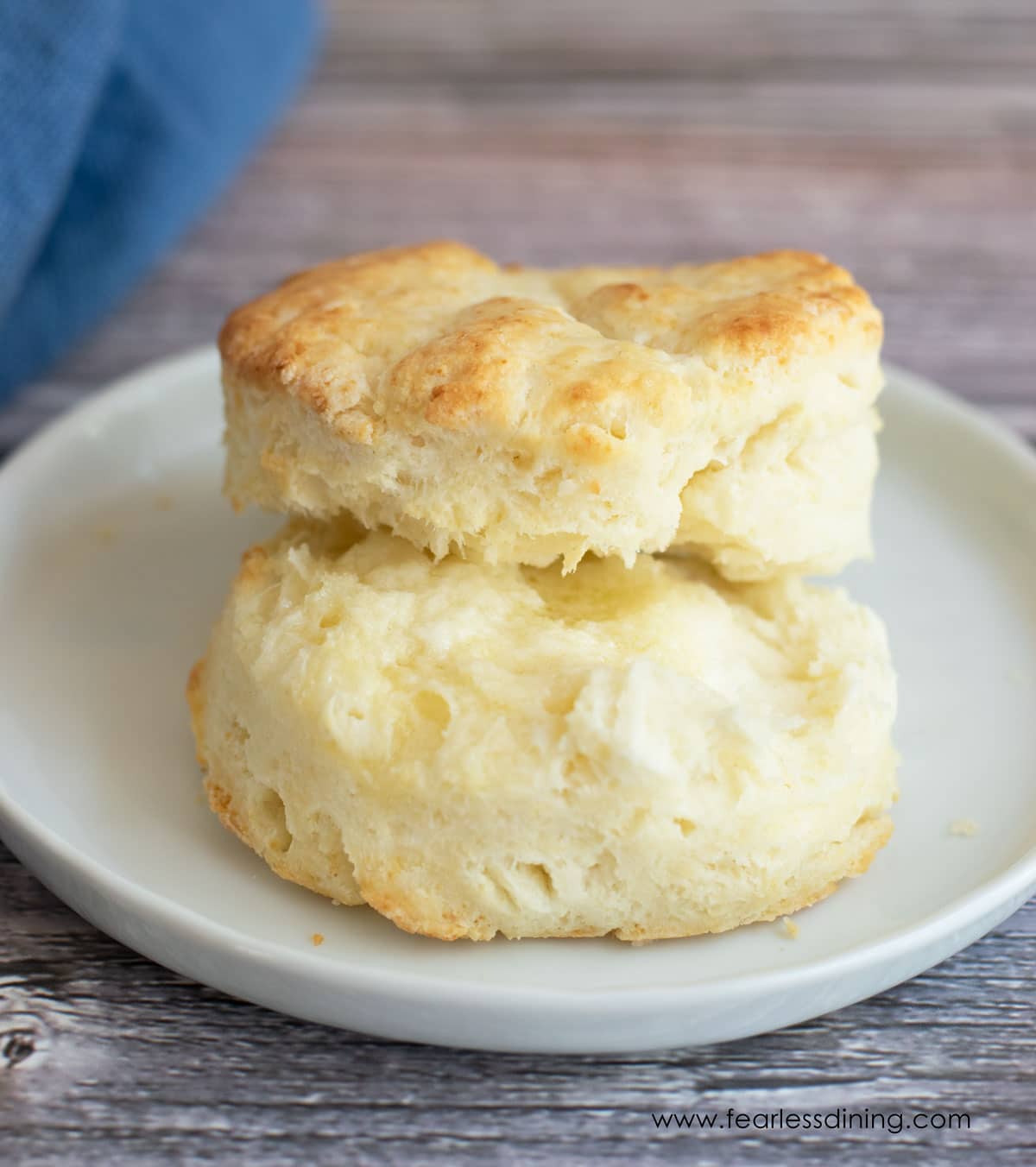 A biscuit cut in half on a plate with butter.