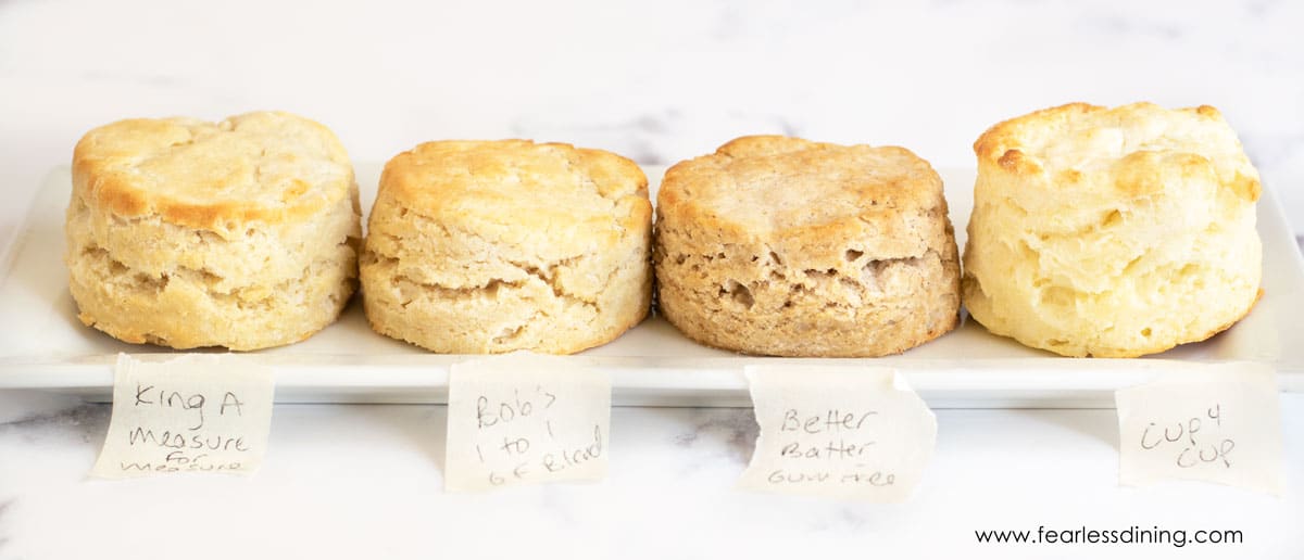 A row of four gluten free biscuits on a rectangular shaped plate.