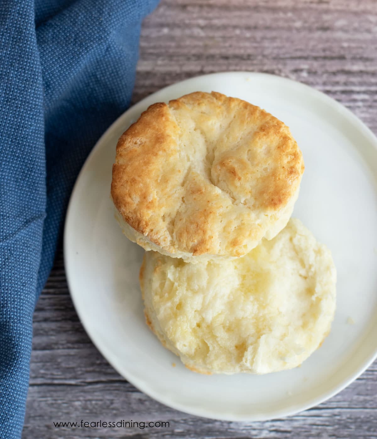 A cut biscuit on a plate with butter.
