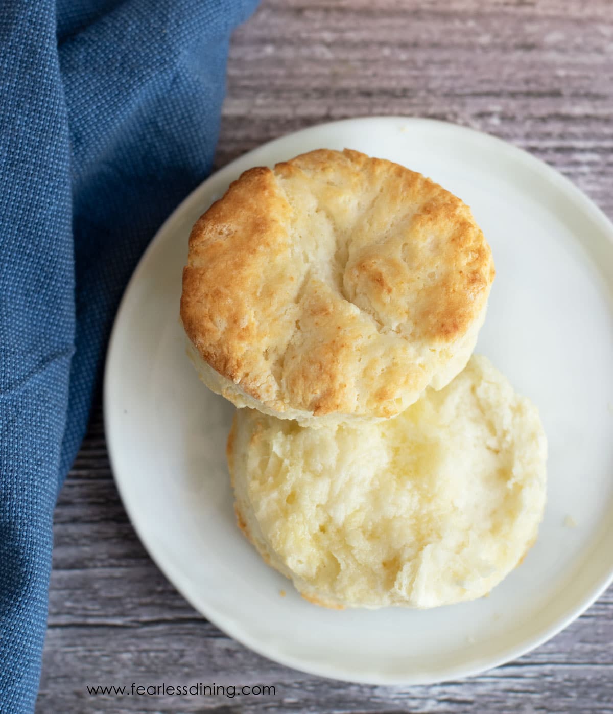 A cut biscuit on a plate ready for strawberries and cream.