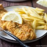 An air fried catfish filet on a plate with french fries.