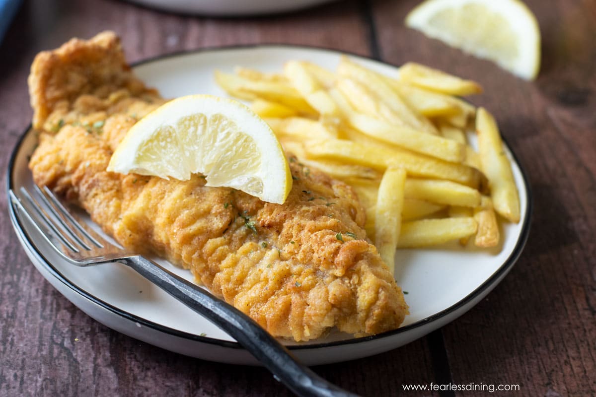 An air fried catfish filet on a plate with french fries.