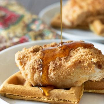 Pouring syrup over chicken and waffles.