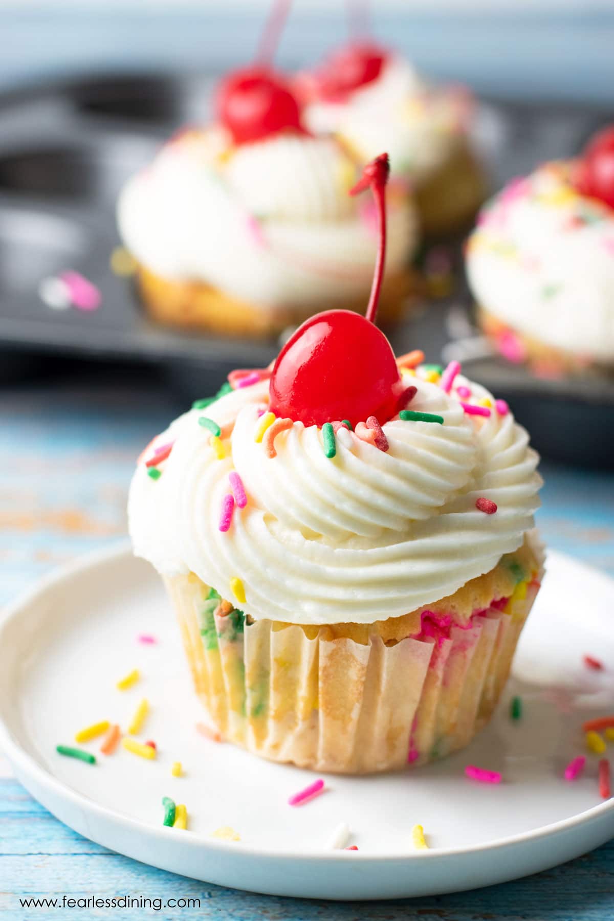 A gluten free funfetti cupcake on a small white plate.