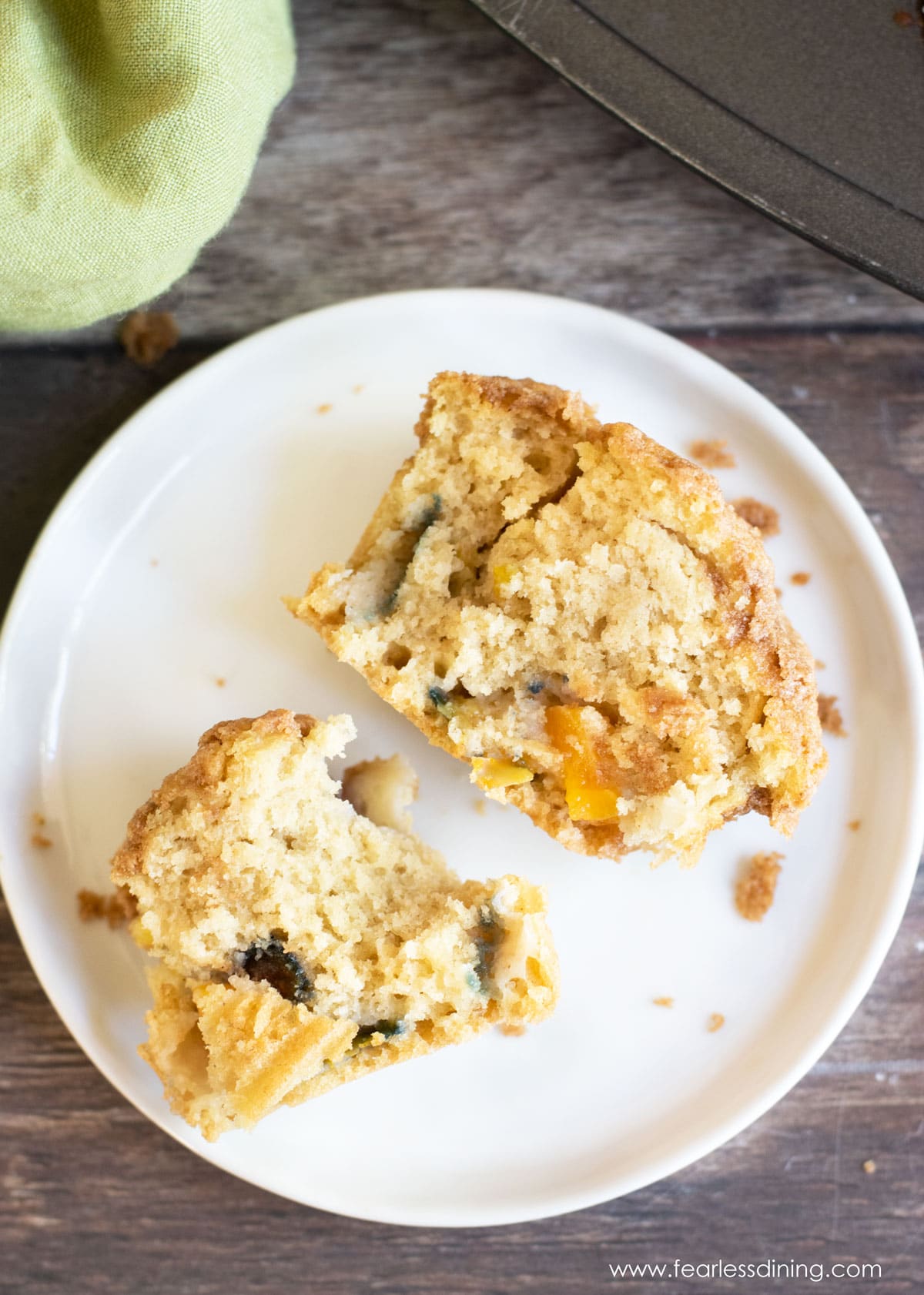 A peach muffin cut in half on a plate.