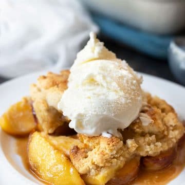 A plate full of peach cobbler topped with ice cream.