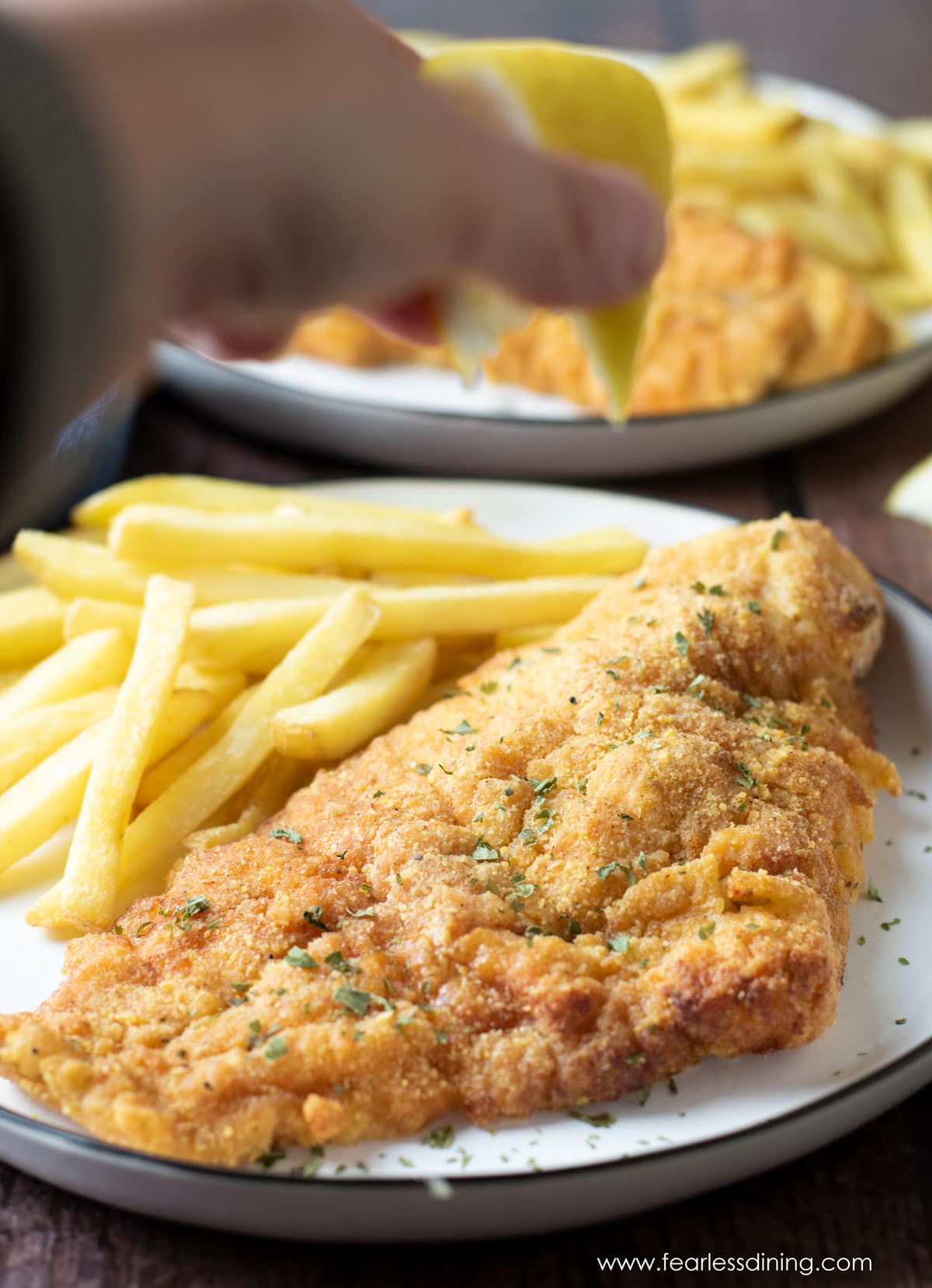 Squeezing lemon juice over a piece of fried catfish.