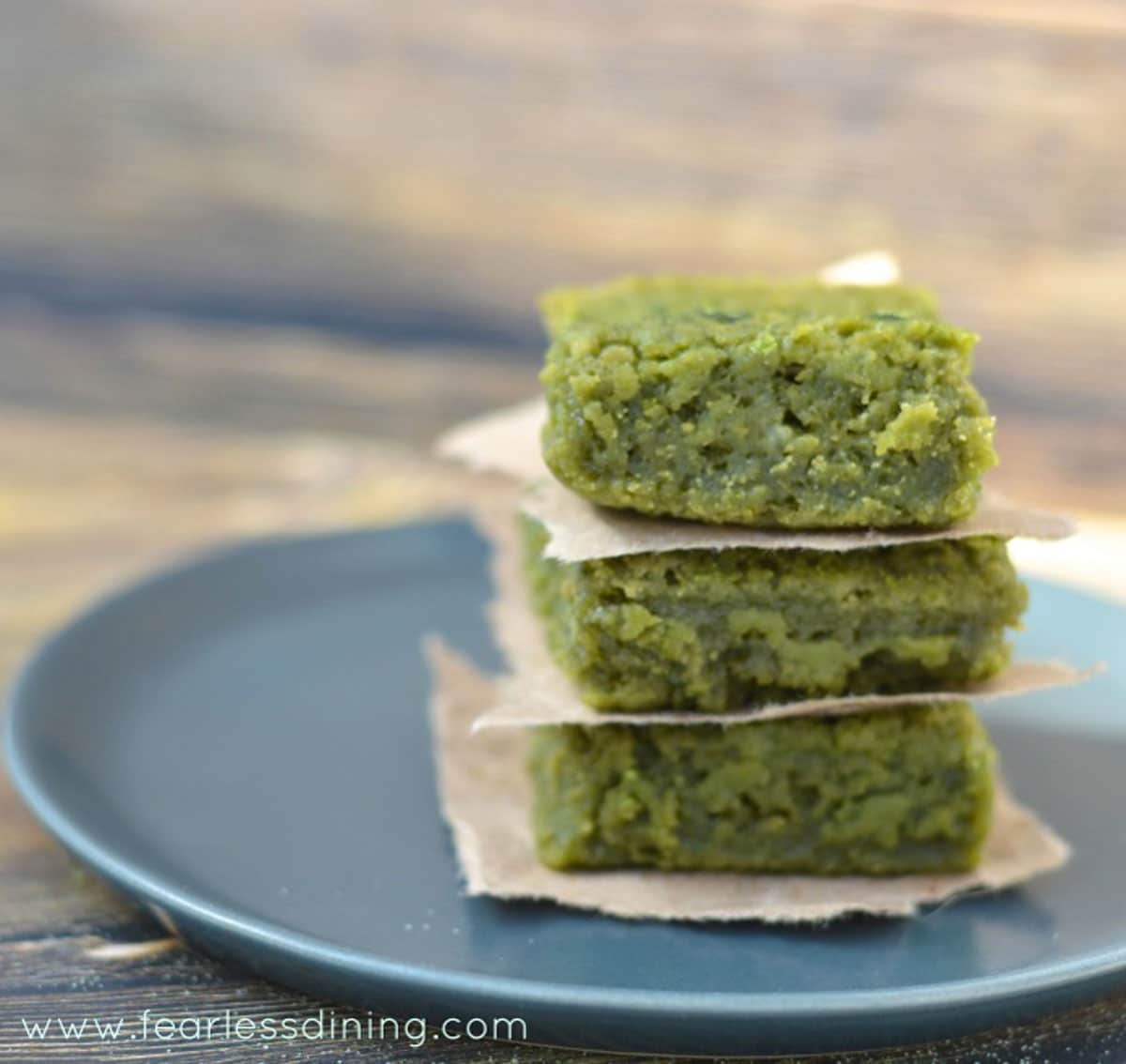 A stack of 3 pieces of matcha mochi on a grey plate.