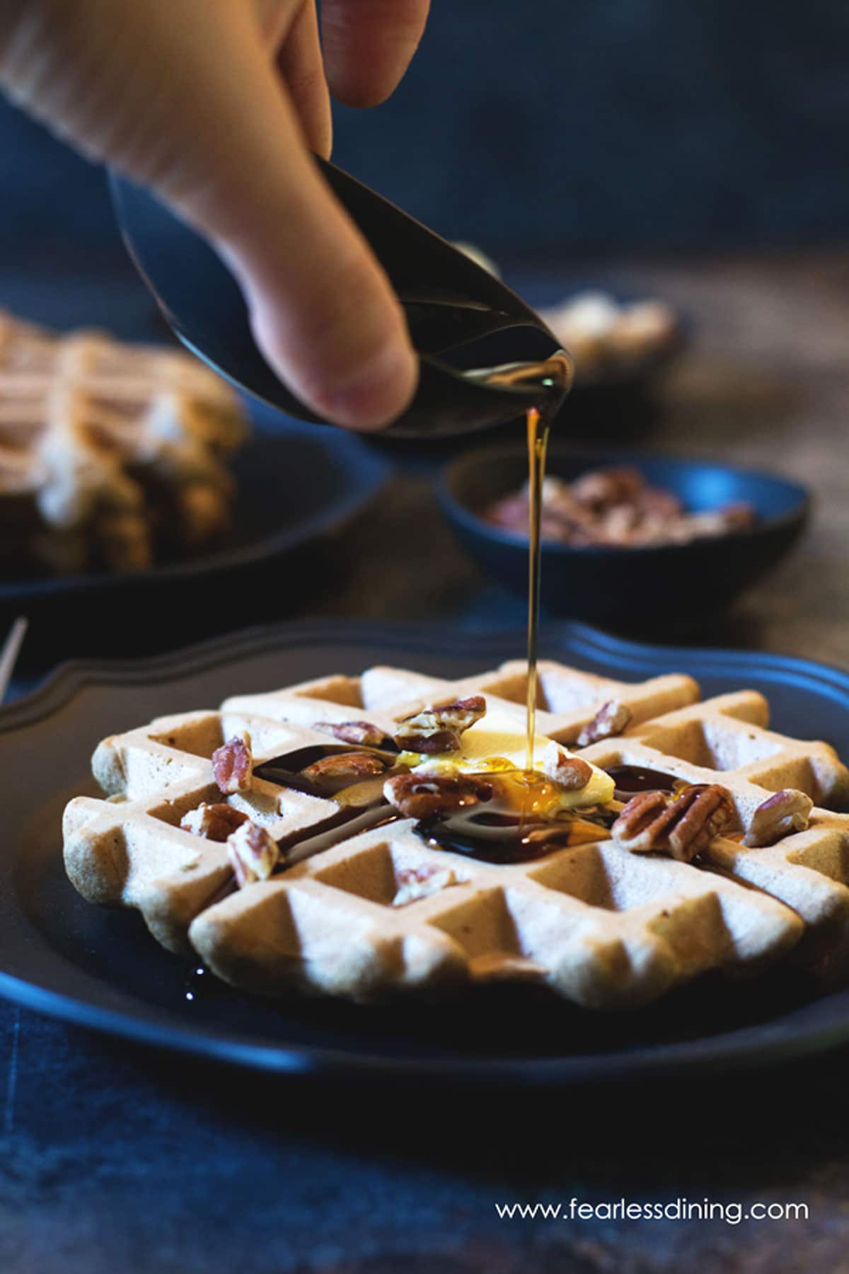 Pouring syrup on banana flour waffles.