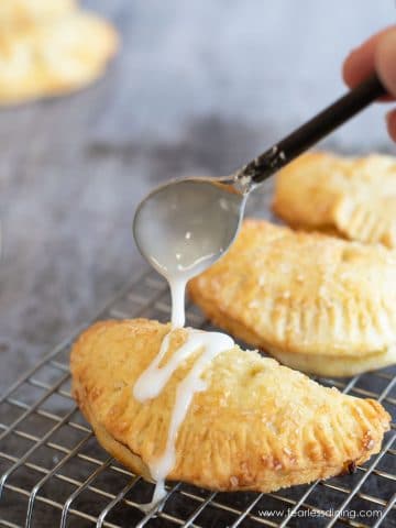 Drizzling icing over a gluten free air fried hand pie.