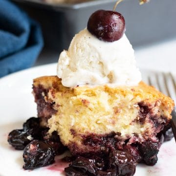A serving of gluten free cake mix cherry cobbler topped with vanilla ice cream.