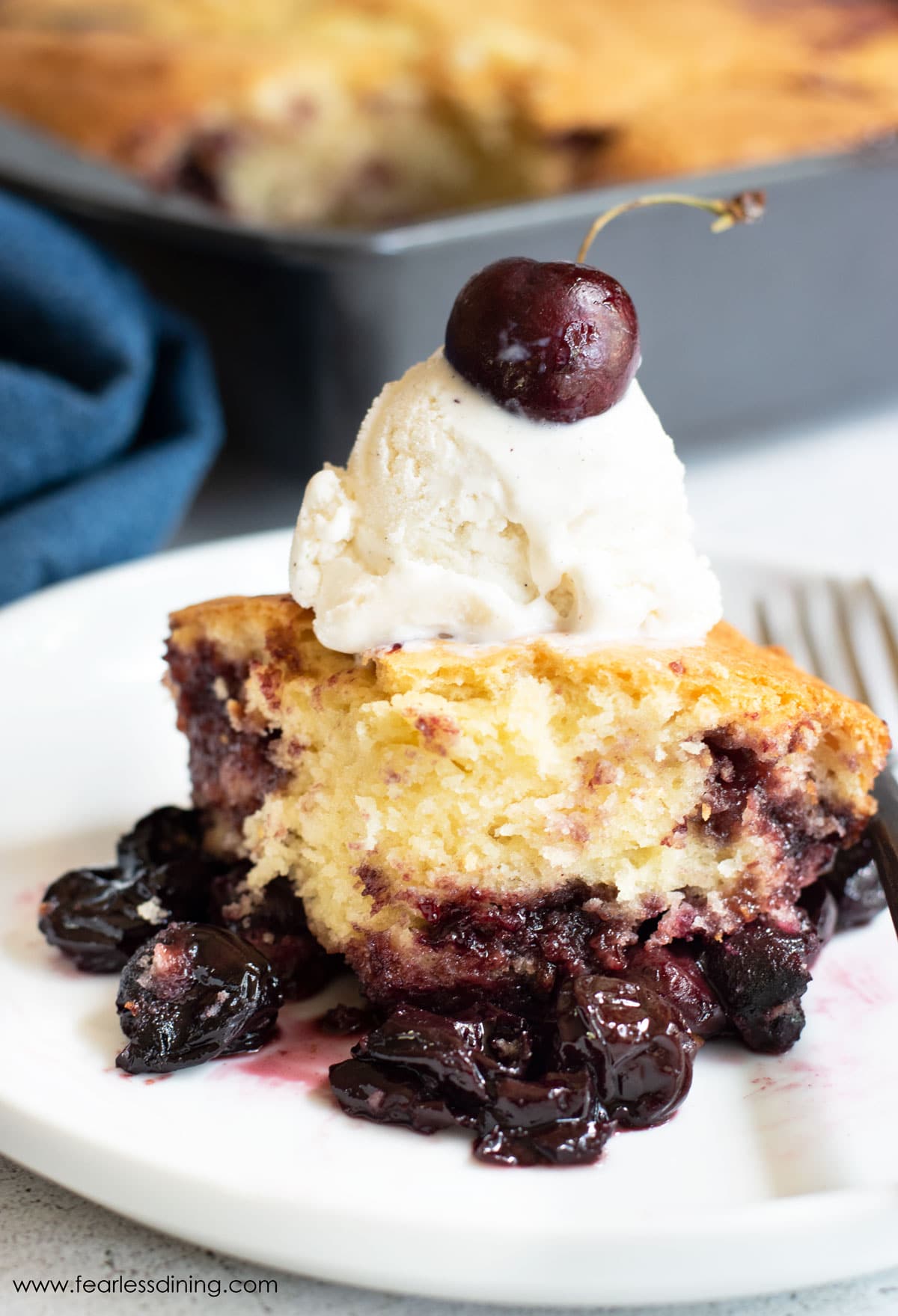 A serving of gluten free cake mix cherry cobbler topped with vanilla ice cream.