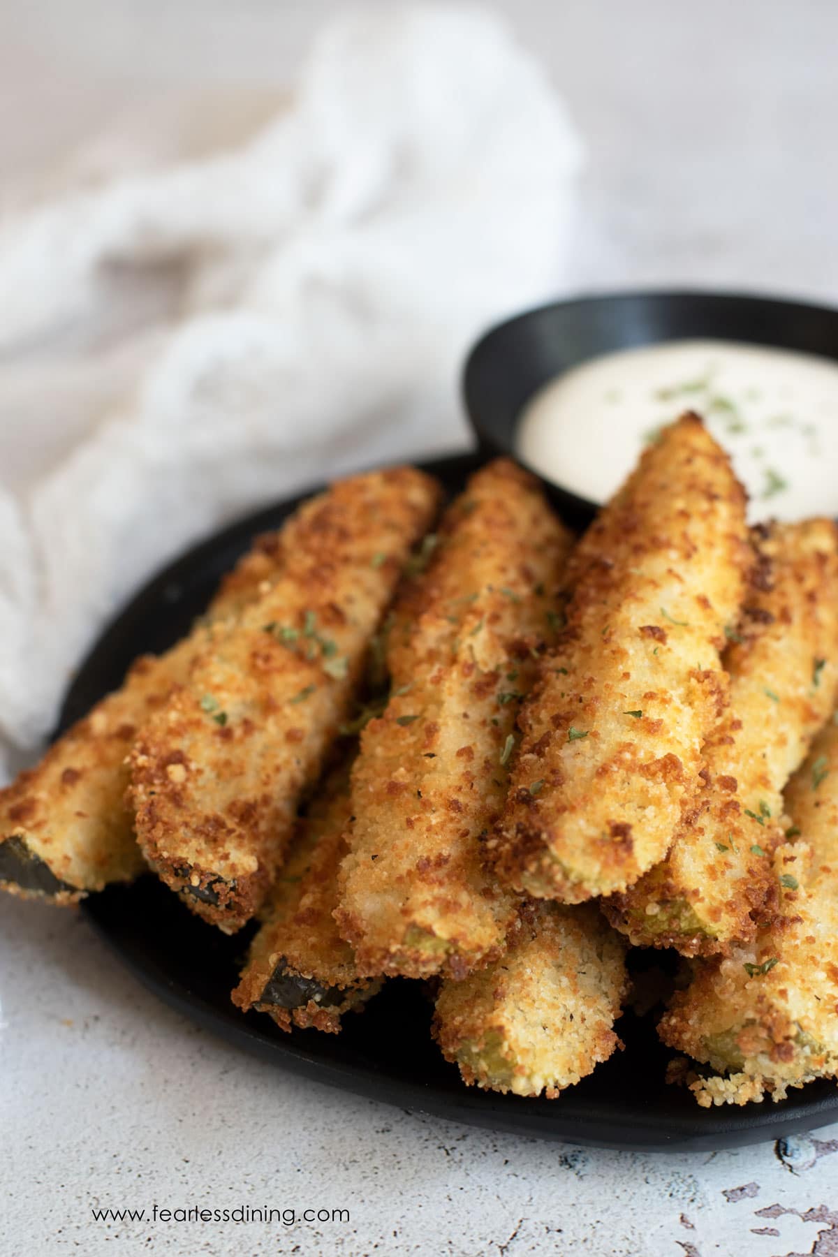 A platter of gluten free fried pickles and ranch dressing.