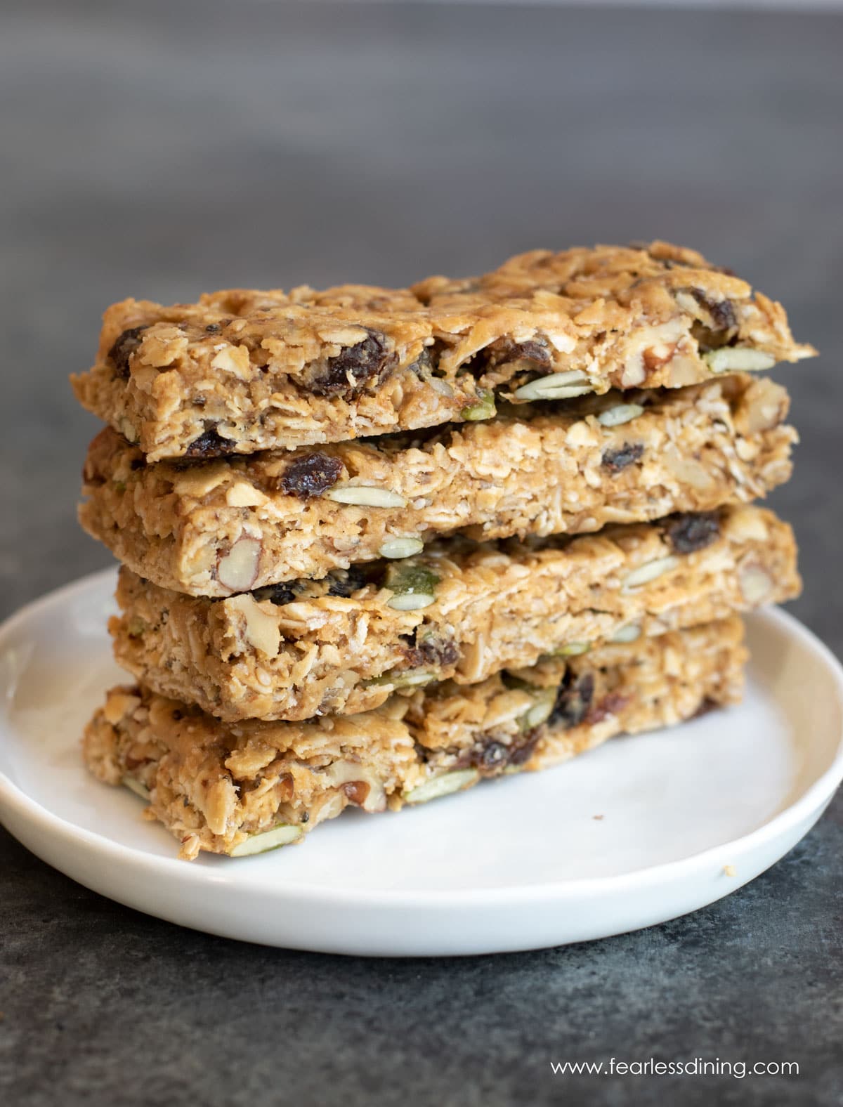 A stack of four gluten free granola bars on a small white plate.