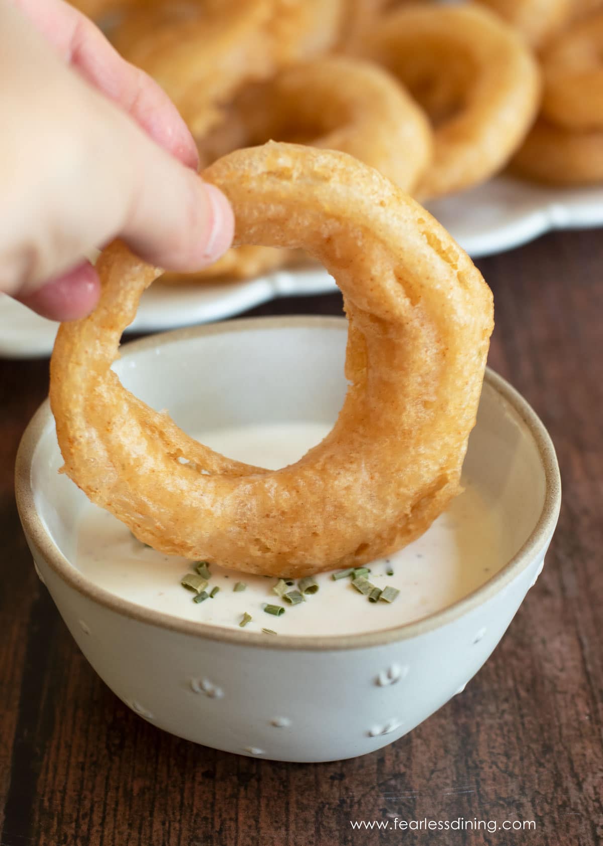 Dipping a fried gluten free onion ring in ranch dressing.