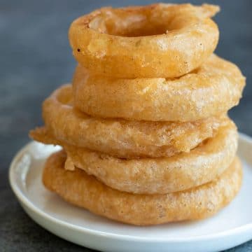 A stack of six large gluten free onion rings.