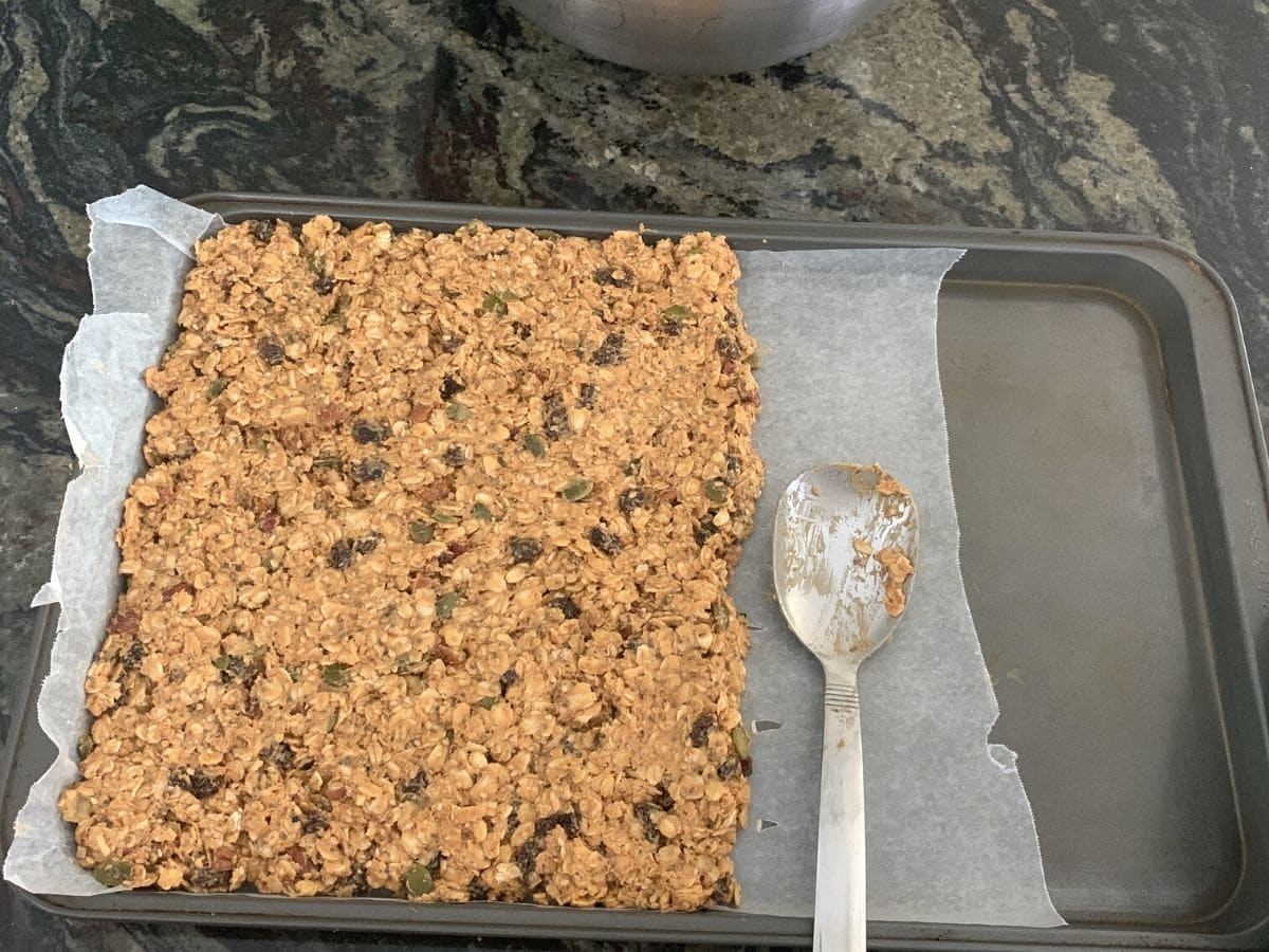 Granola bars on a prepared cookie sheet ready to chill in the refrigerator.