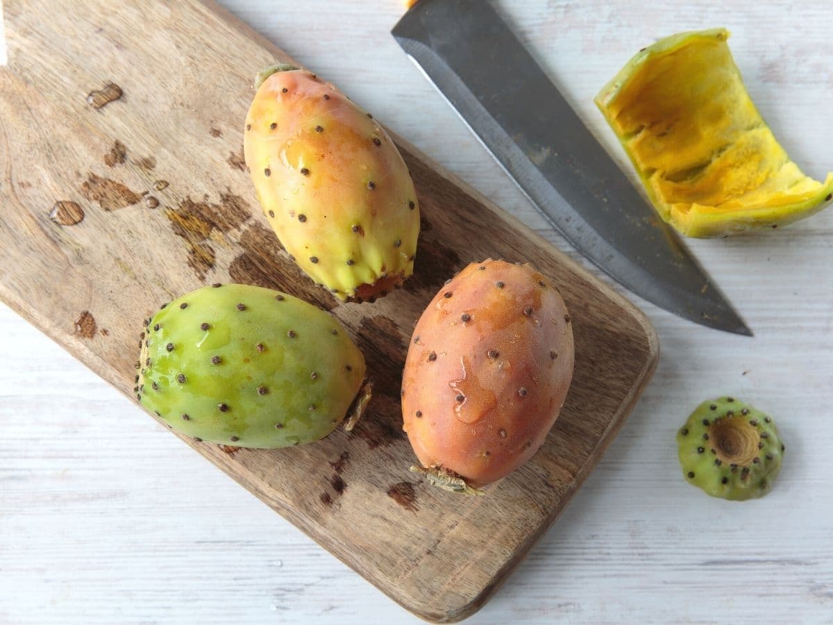 Cutting a prickly pears on a wooden cutting board.