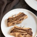 Two bat shaped pumpkin shortbread cookies on a plate.