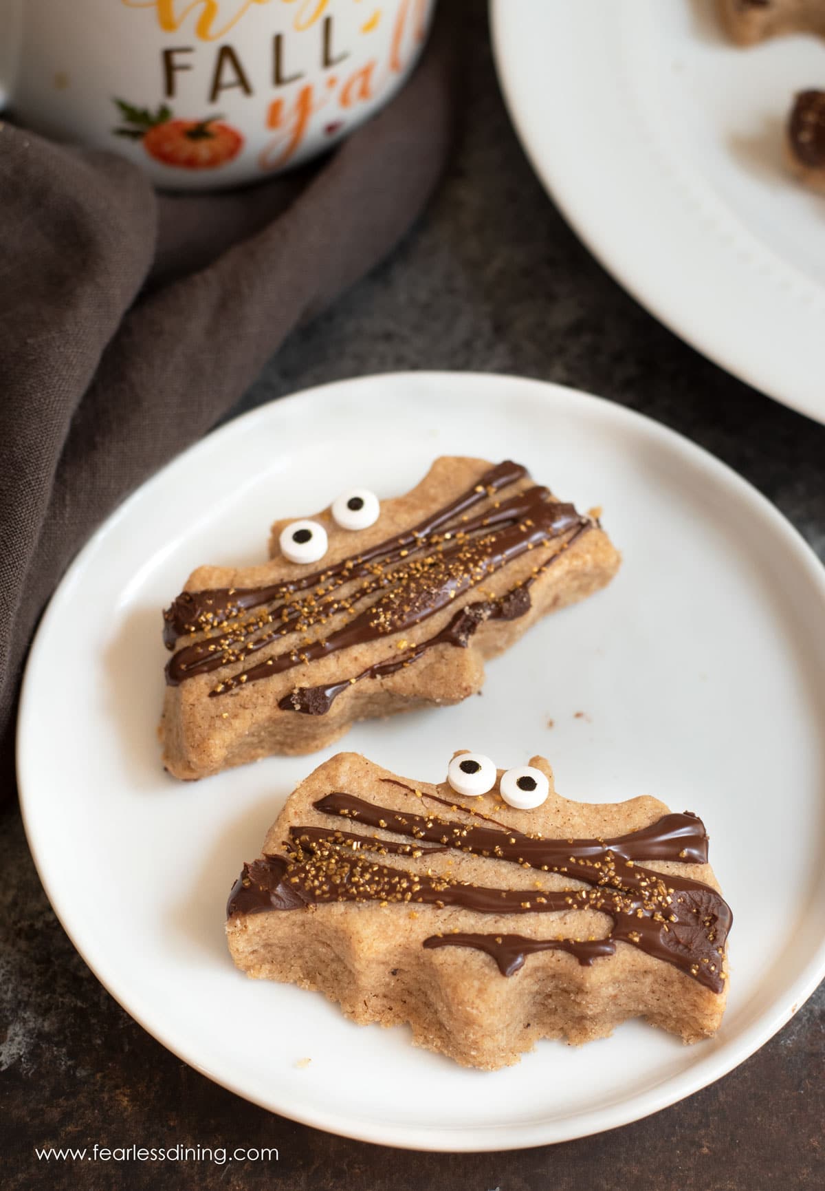 Two bat shaped pumpkin shortbread cookies on a plate.