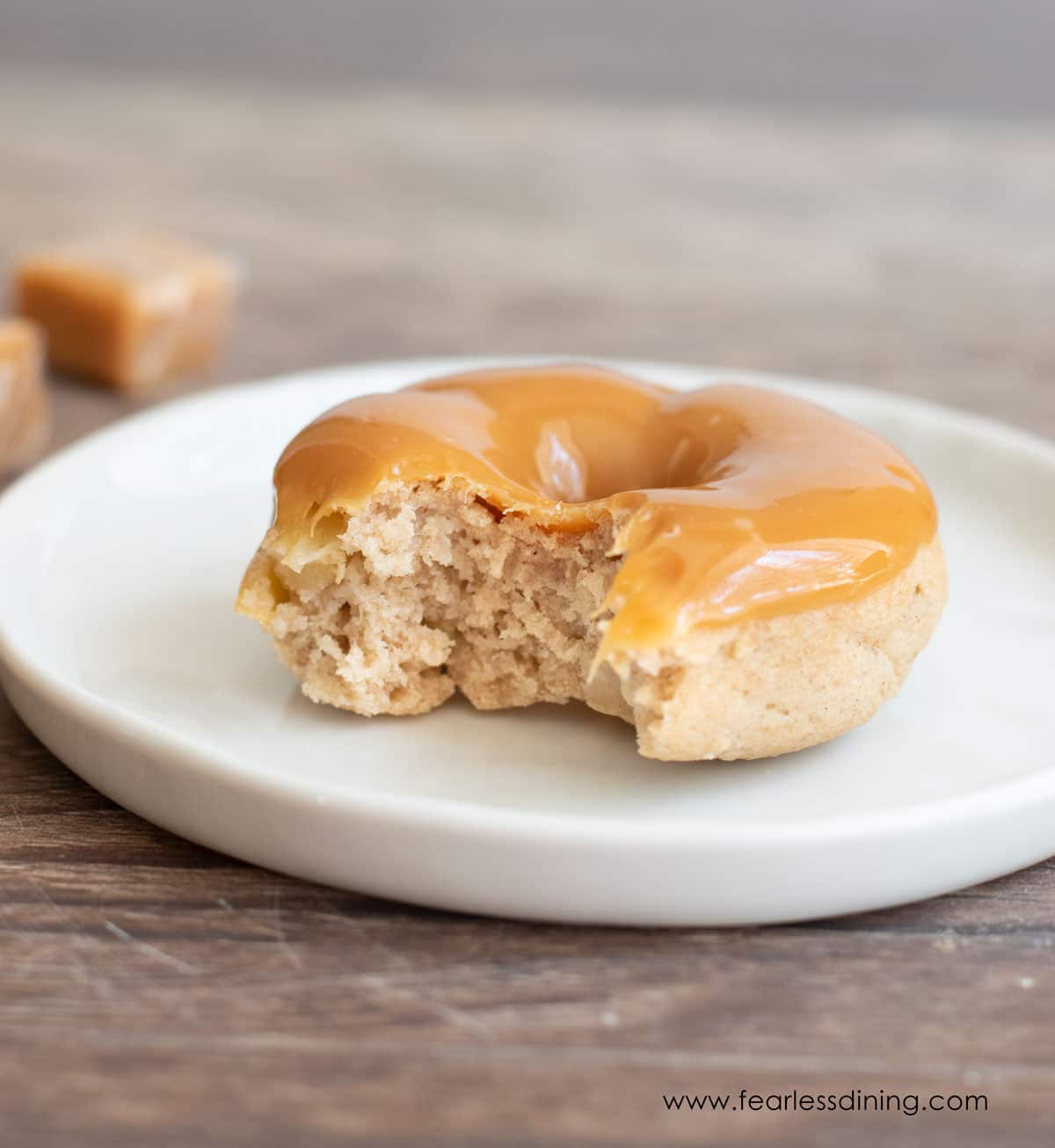 a caramel apple donut on a plate with a bite taken out