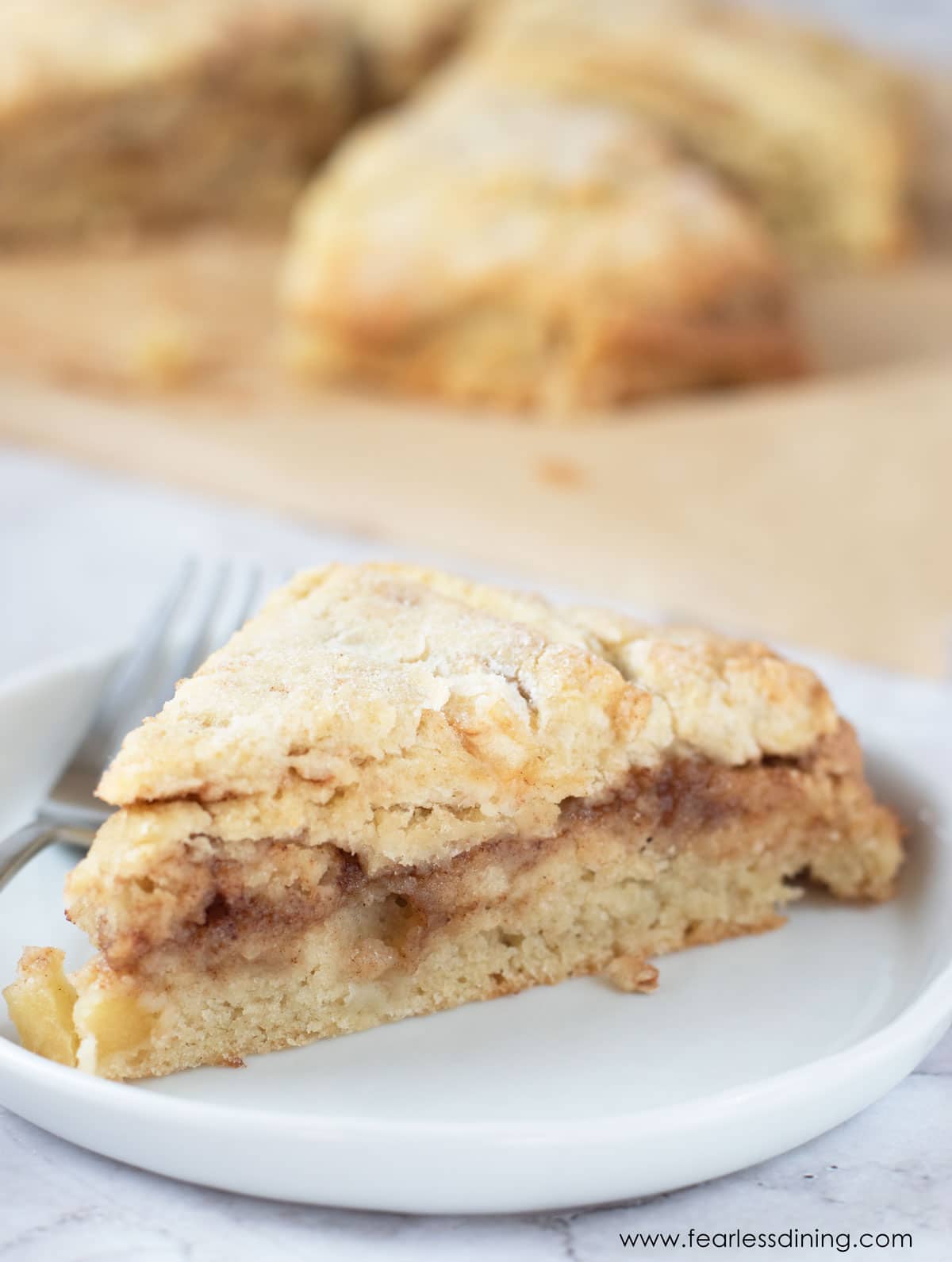 A gluten free cinnamon apple scone on a white plate.