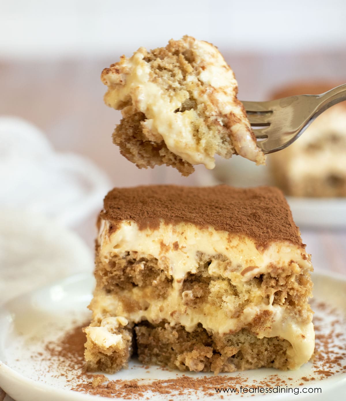 A fork holding up a bite of gluten free tiramisu.