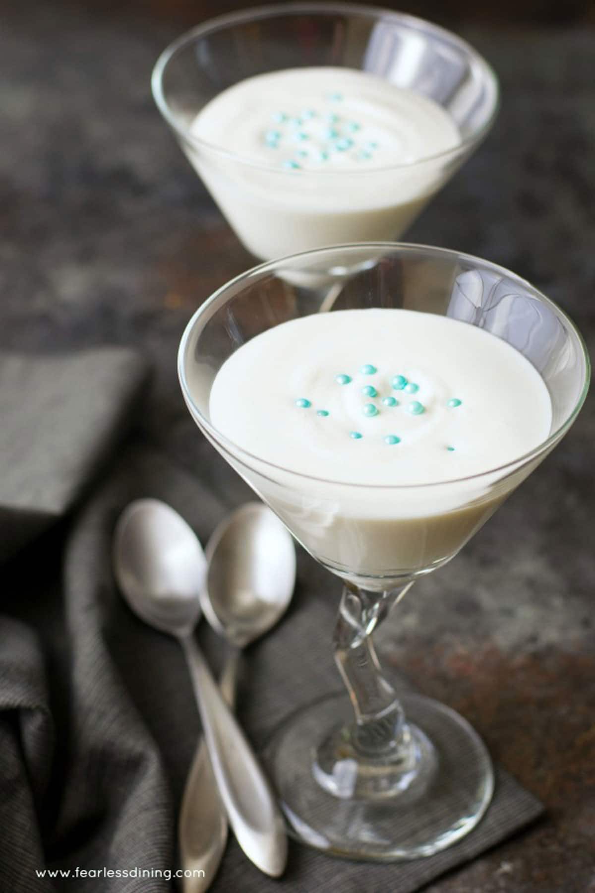 Two martini glasses filled with vanilla mousse on a table.