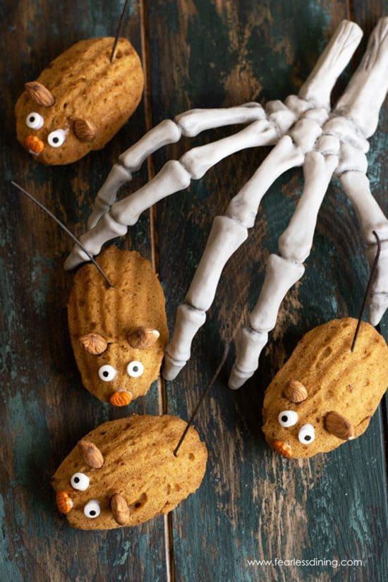 Pumpkin madeleines decorated as Halloween mice next to a skeleton hand.