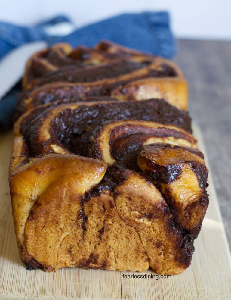 A baked gluten free babka on a wooden cutting board.