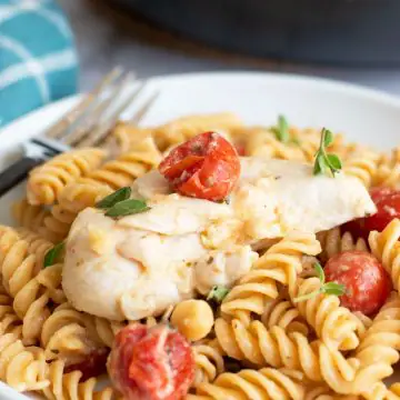 a plate of chicken pasta with feta and tomatoes