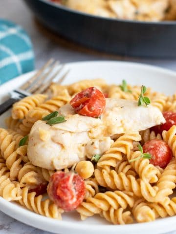 A plate of chicken pasta with feta and tomatoes.