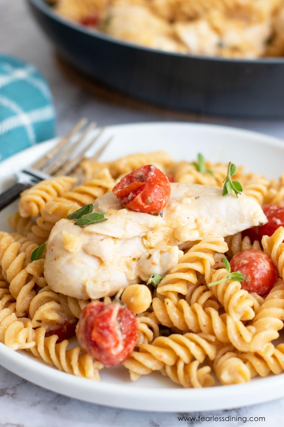 A plate of gluten free chicken pasta with feta and tomatoes.