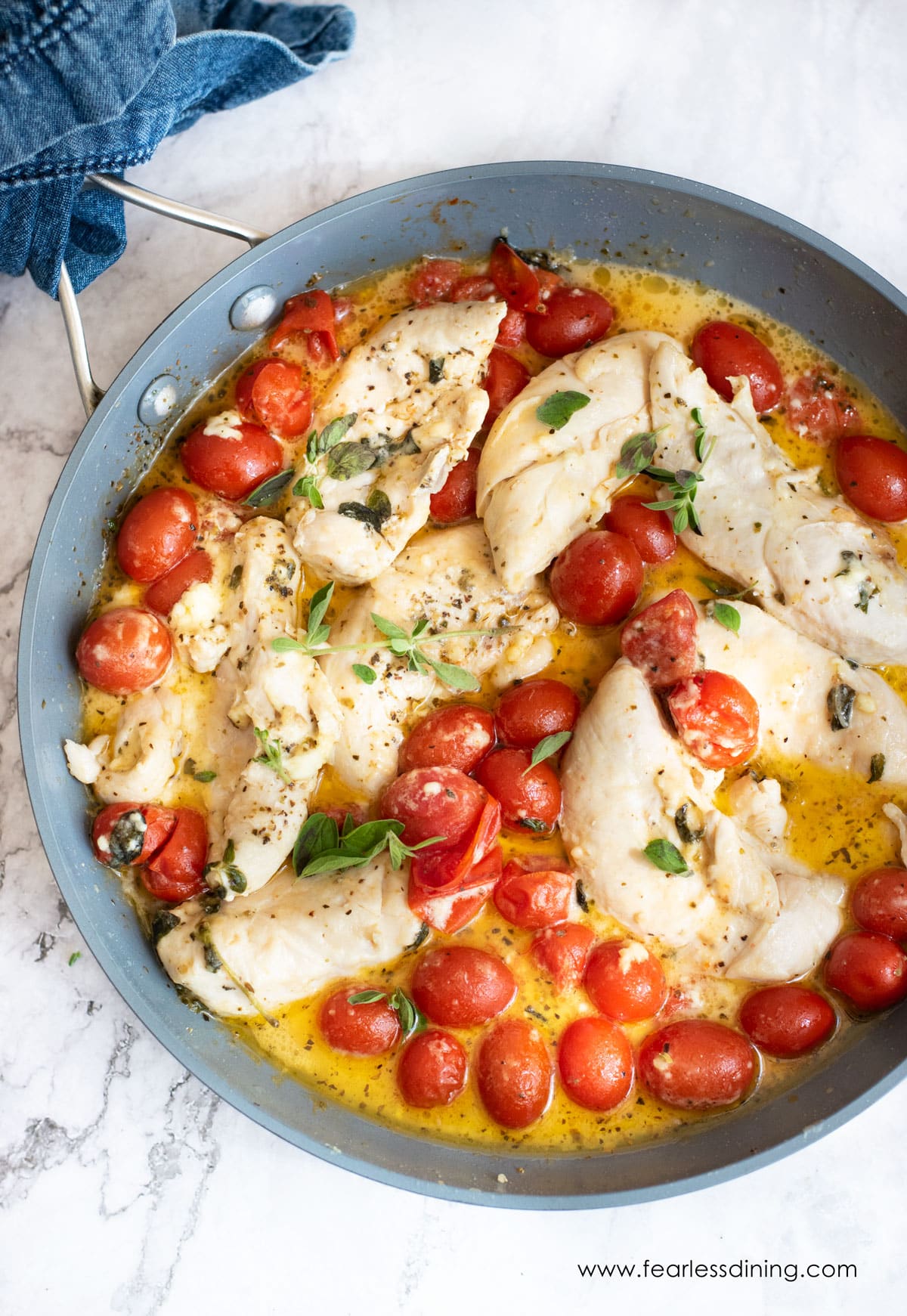 a skillet with cooked chicken and tomatoes in a feta cheese sauce