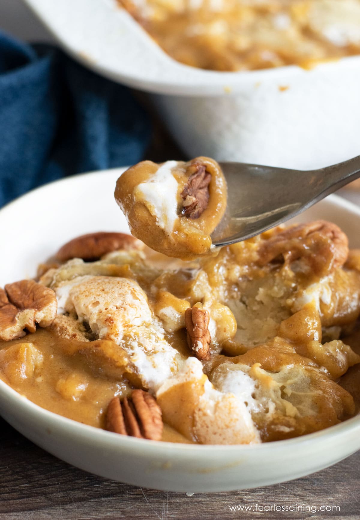 A spoon holding up a bite of pumpkin cobbler.