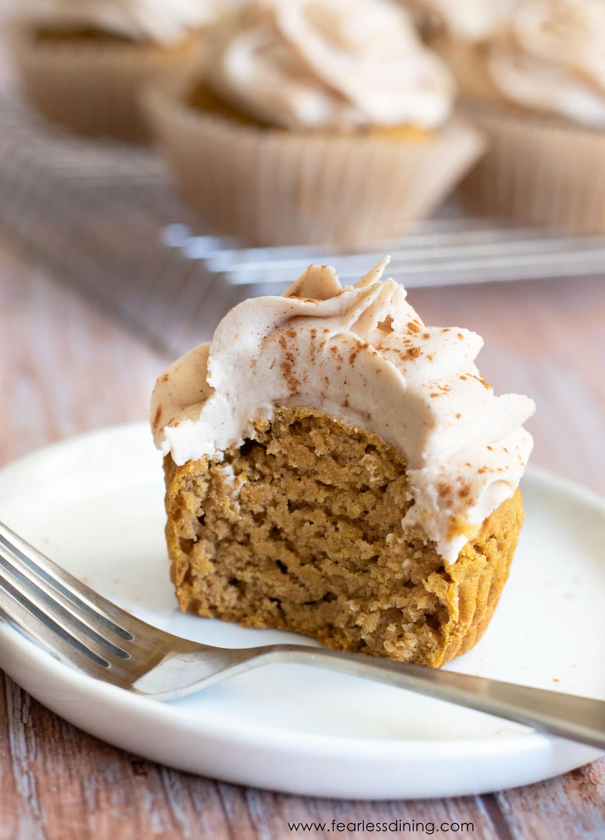 Half of a pumpkin cupcake on a white plate.