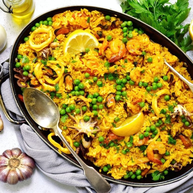 A large serving pan full of paella on a table.