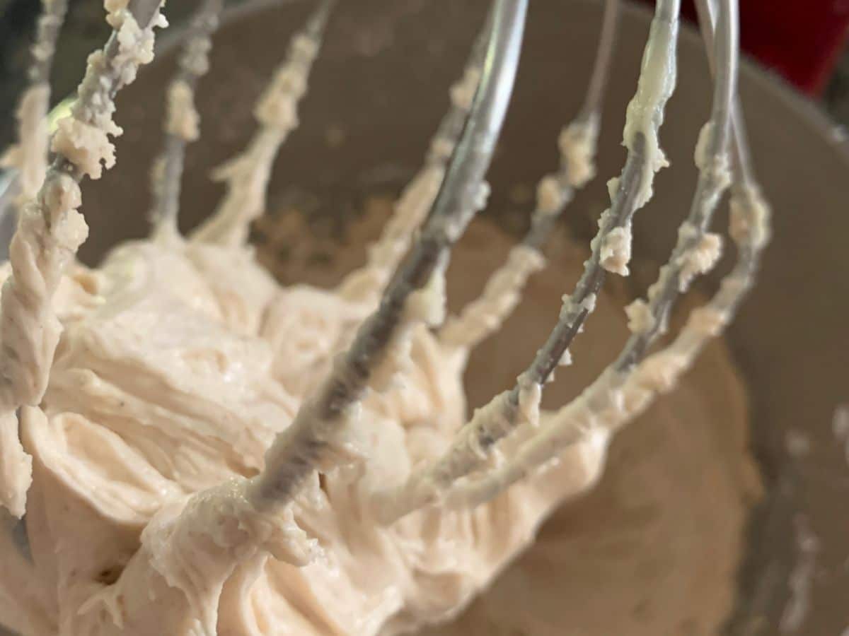 Cinnamon frosting on a stand mixer whisk attachment.