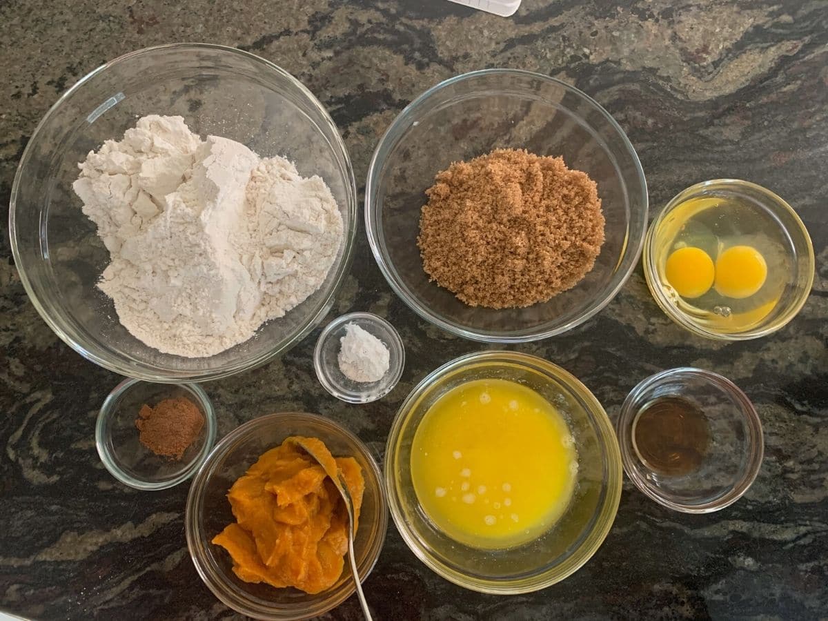 The ingredients to make gluten free pumpkin muffins in small glass bowls.