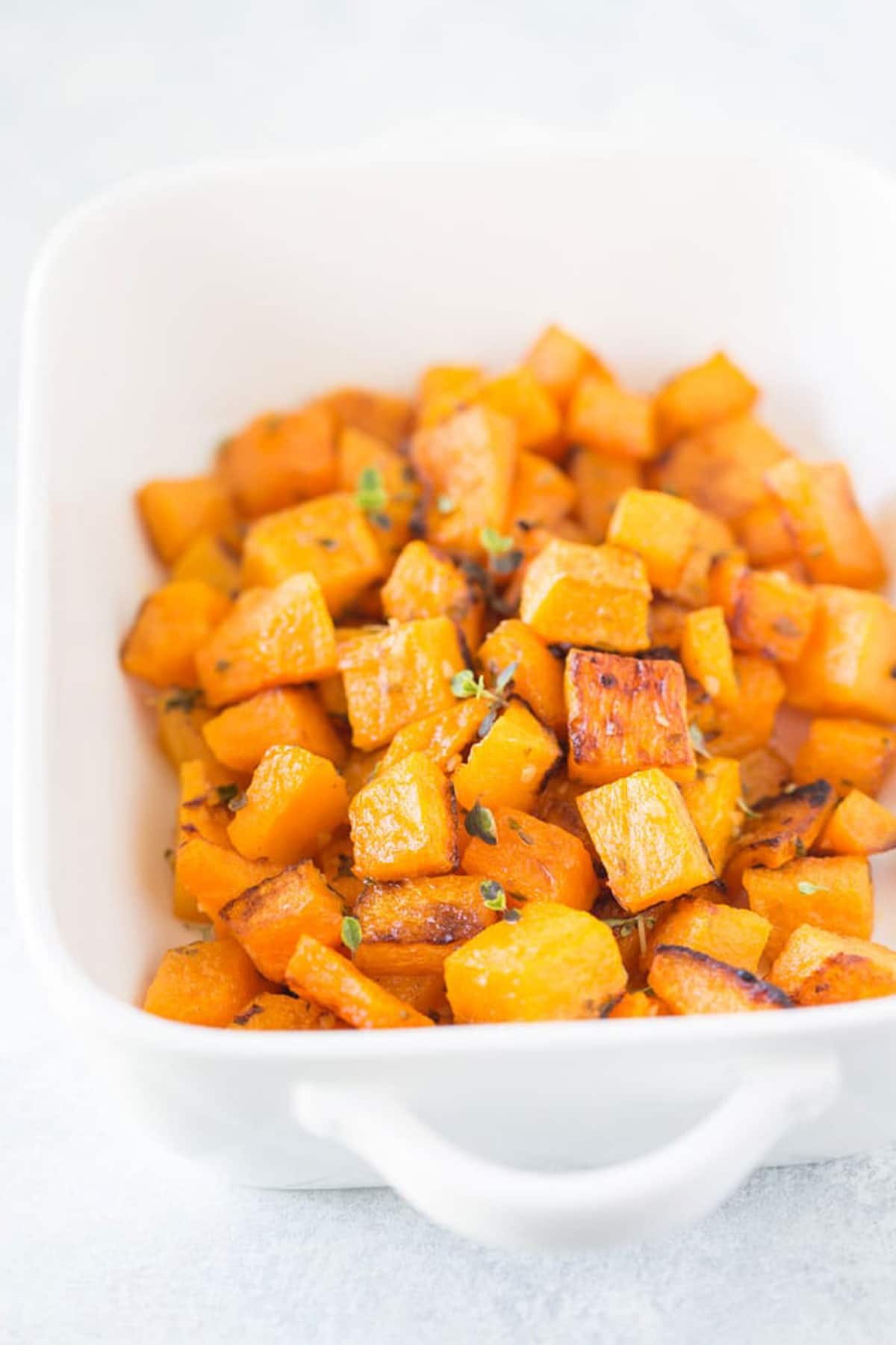 A white baking dish with roasted butternut squash.