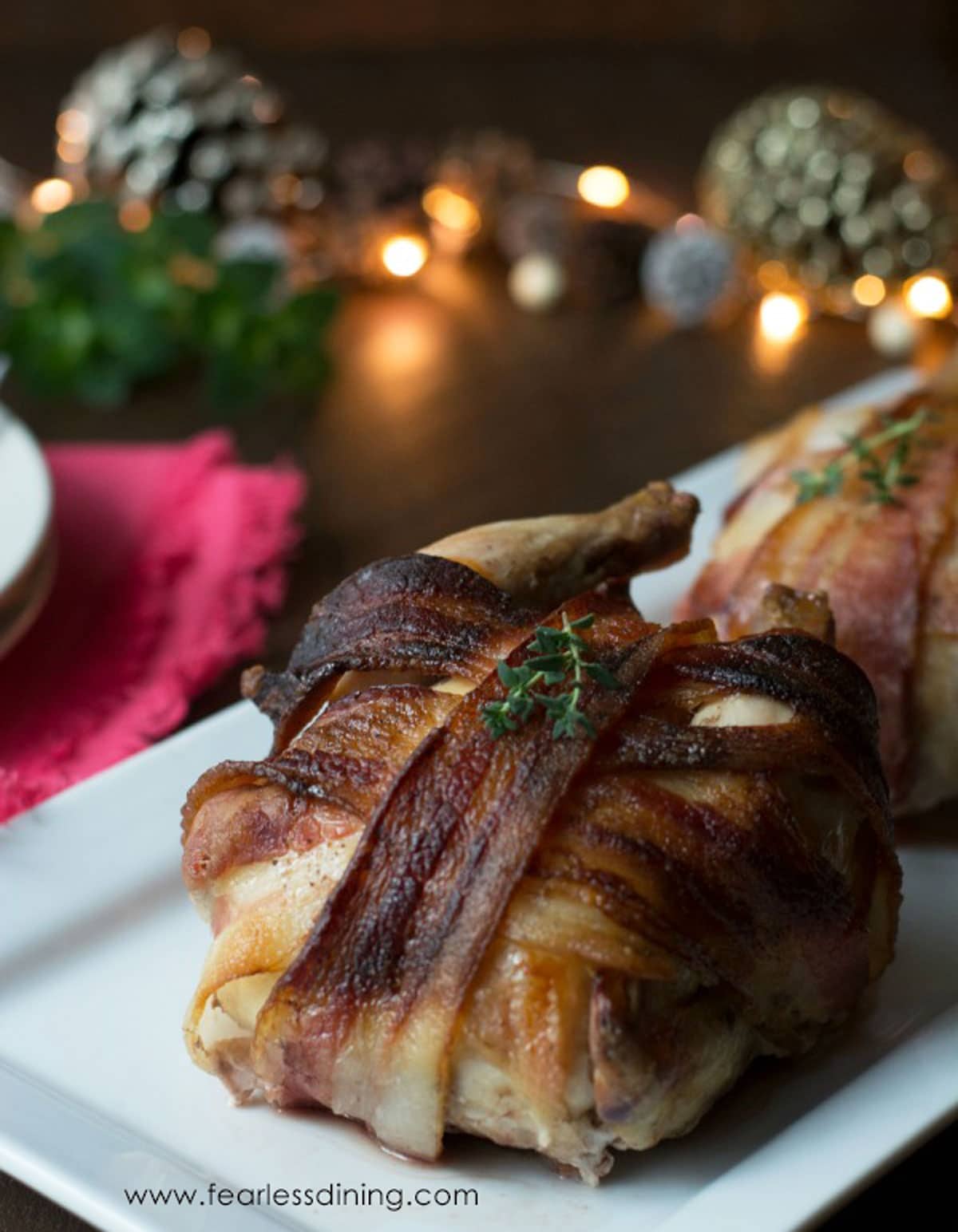 Two bacon wrapped cornish hens on a platter.