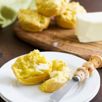 A cornbread muffin cut in half with butter spread on it.