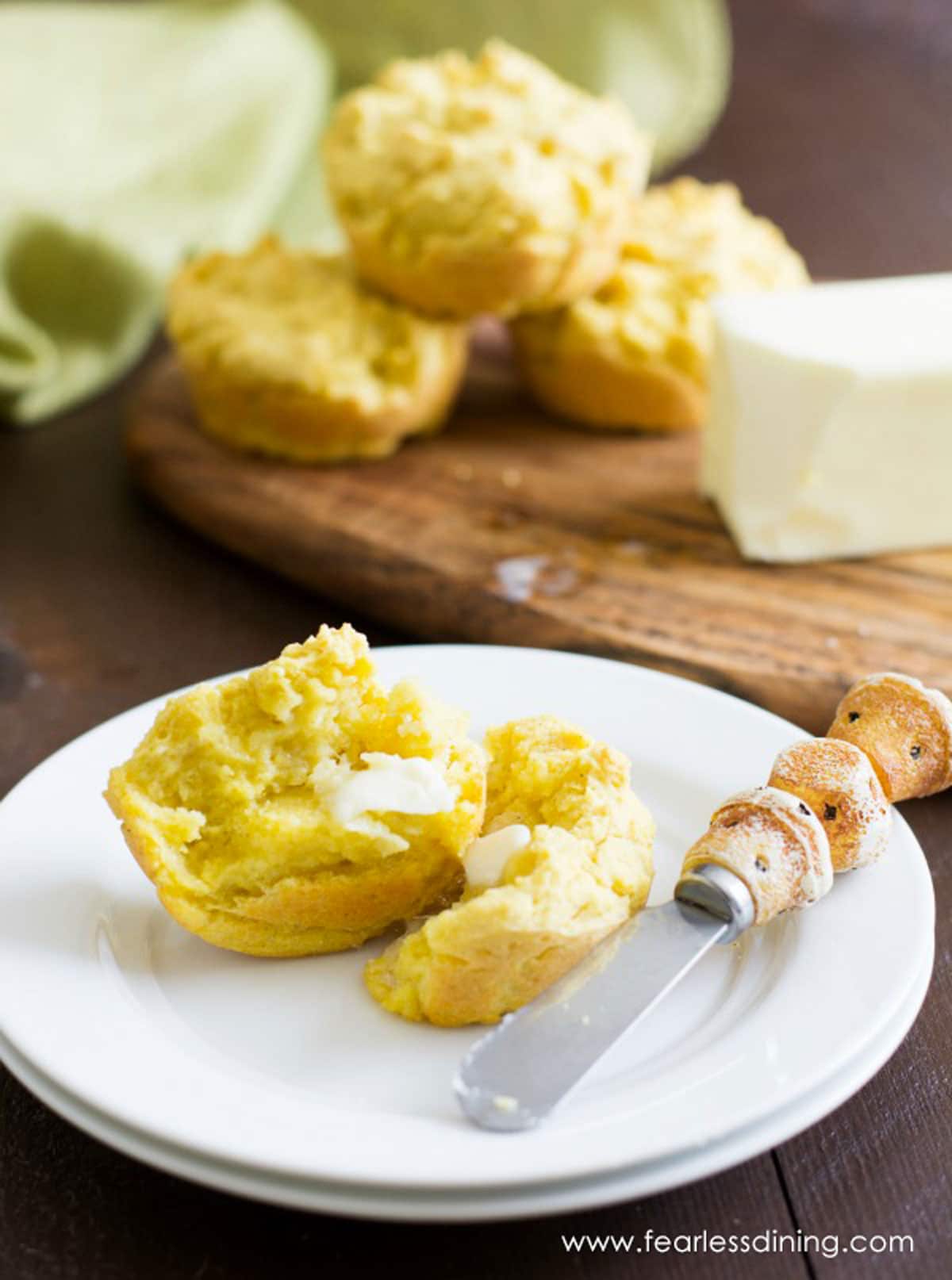 A cornbread muffin cut in half with butter spread on it.