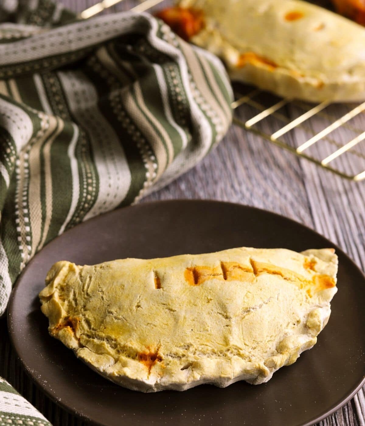 a baked gluten free calzone on a brown plate.